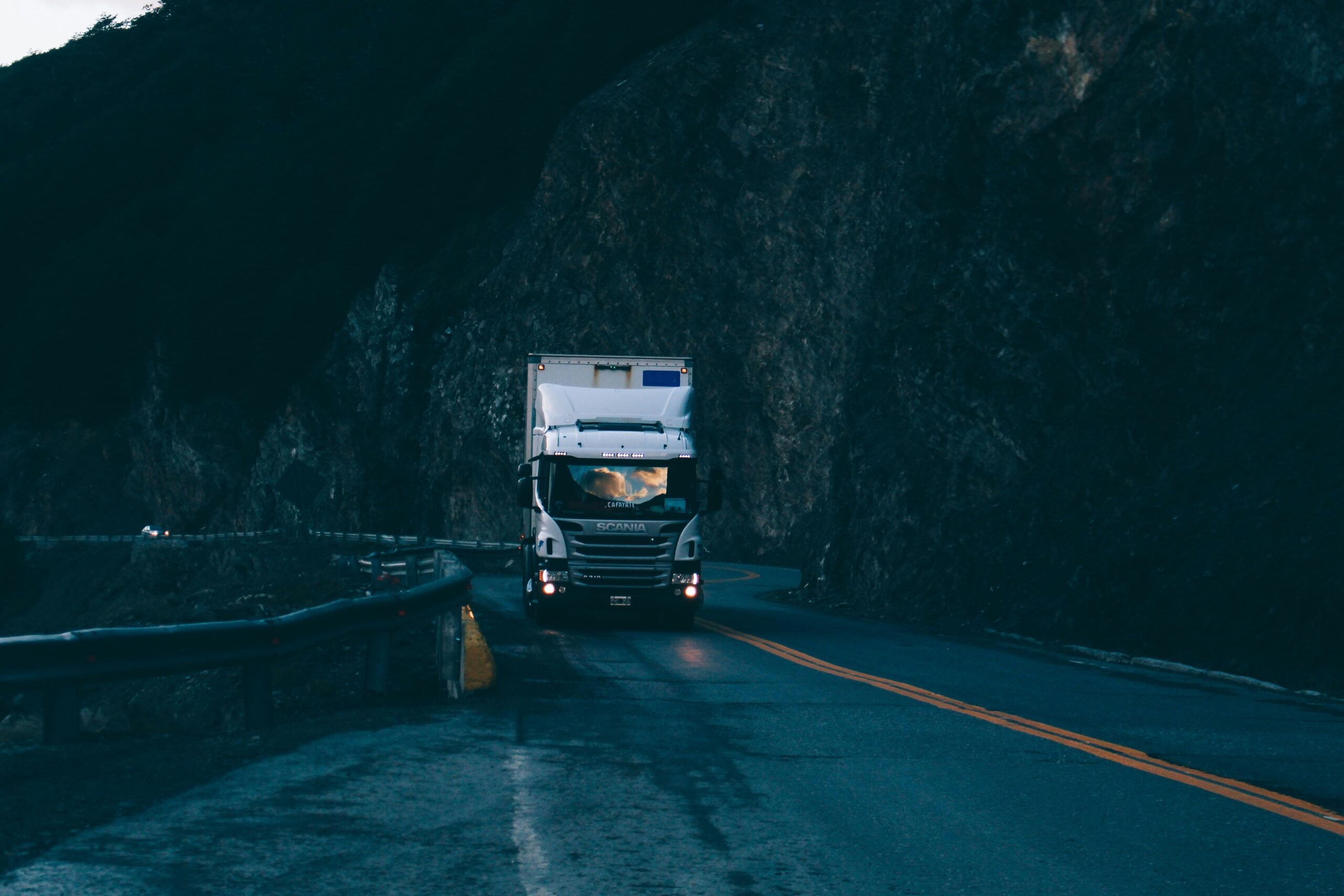 A truck traveling down a mountainous road, showcasing a steep descent and a picturesque landscape.